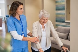 Elderly resident walking through an ALF with staff help