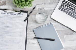 Home Insurance Policy Form on Table with Laptop and Notebook