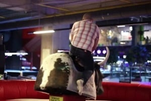 man in check shirt riding mechanical bull