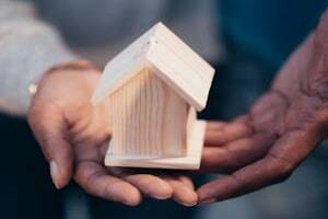Person Holding Small Wooden House Model