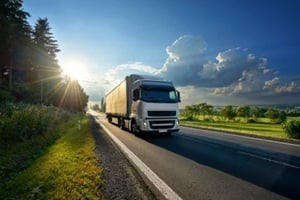 white truck arriving on the asphalt road in rural landscape in the rays of the sunset