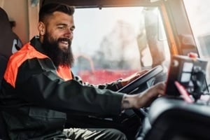 young garbage removal worker driving a waste truck