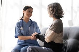 Elderly women talking to a staff member in scrubs inside an assisted living facility